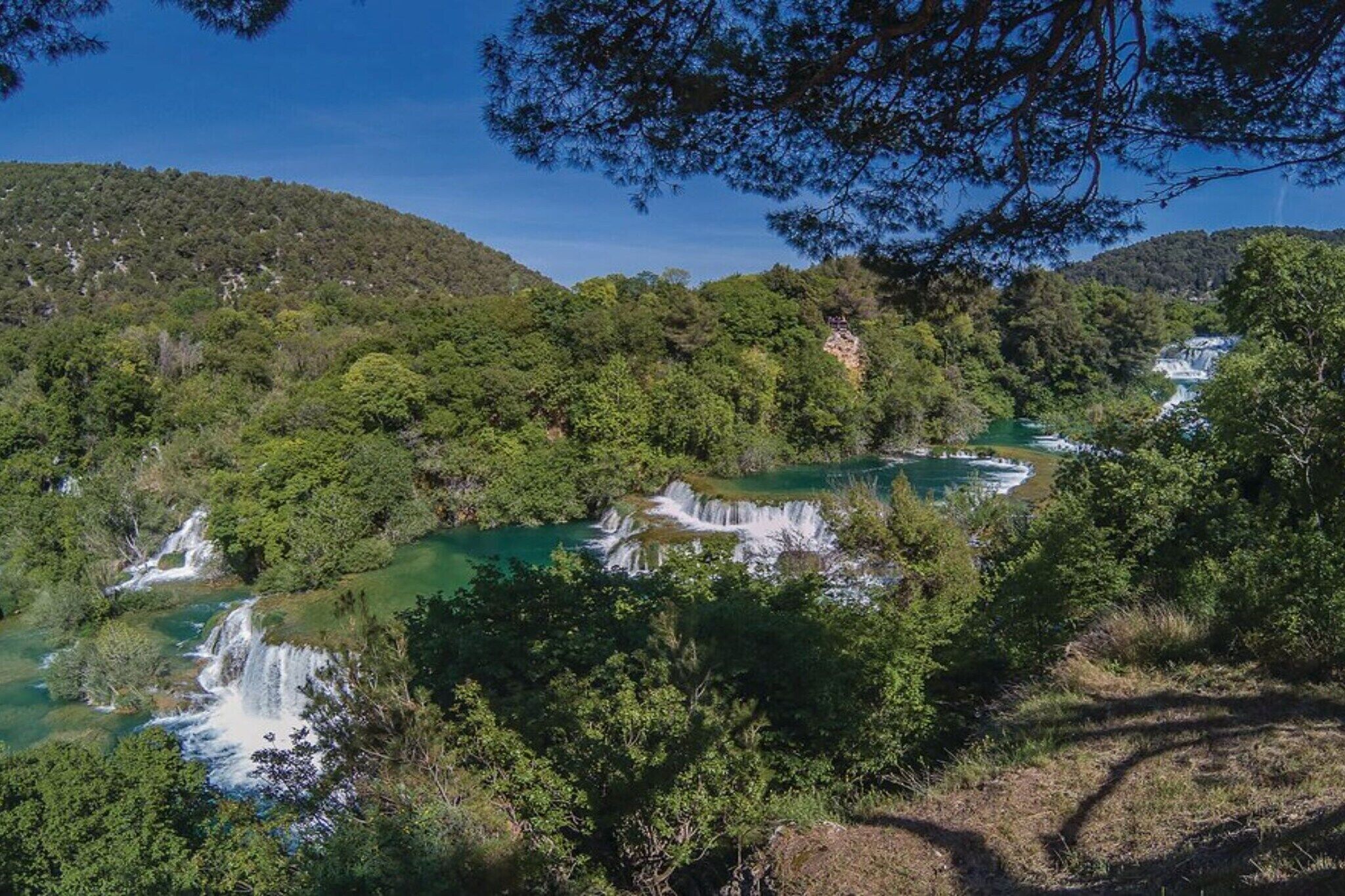 A natural landscape with waterfalls and dense greenery.