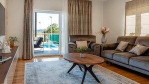 A modern living room with a sofa, armchair, and coffee table. There is a sliding glass door leading to an outdoor area with a pool. - Villa Branka - Villa Tomić Drniš - Siverić (Drnis)