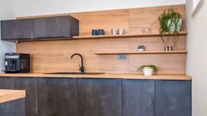 A modern kitchen with dark cabinets, a wooden countertop, a black faucet, and a coffee machine. - Villa Branka - Villa Tomić Drniš - Siverić (Drnis)