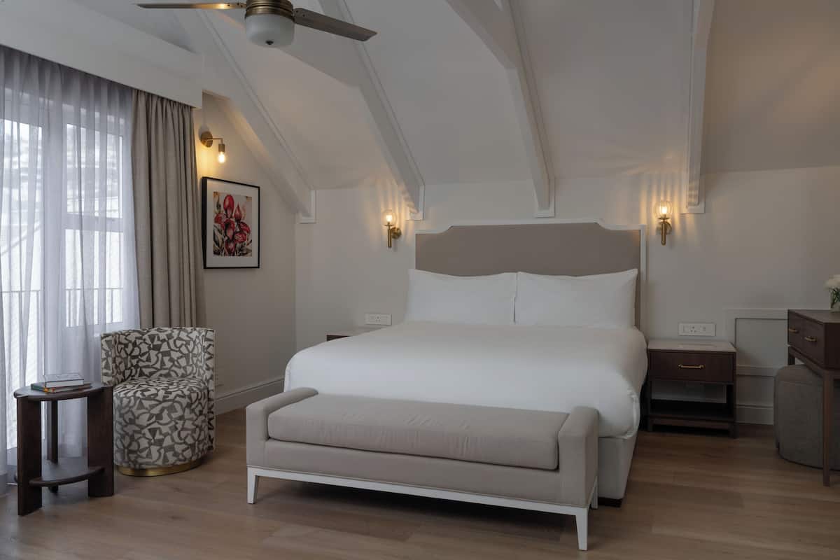 A modern bedroom with a large bed, bedside tables, a chair, and a ceiling fan.