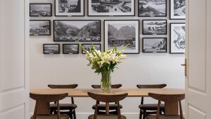 A dining area with a wooden table and chairs, a vase of flowers, and a wall with framed black and white photographs. - Guest House by Morea (Cape Town)