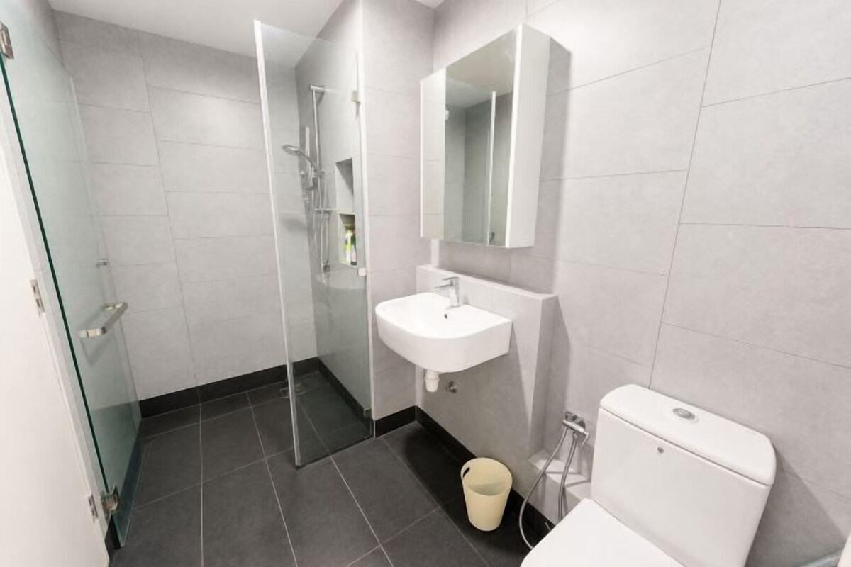 A modern bathroom with a glass shower enclosure, a white sink, and a toilet.