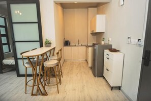A compact kitchen with a dining area, a refrigerator, and a small cabinet. - LS Sunset Ocean View Homestay - Jesselton Quay (Kota Kinabalu)
