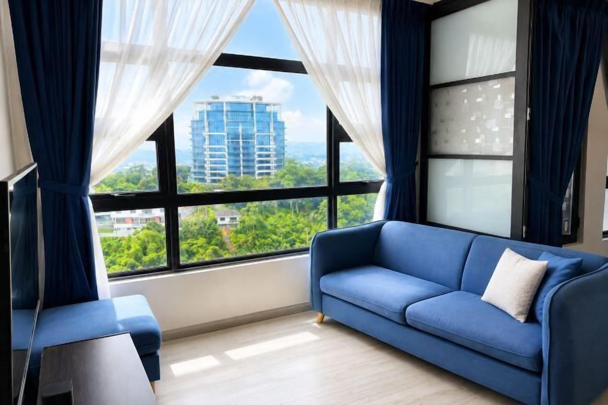 A room with a blue sofa, a small table, and a large window with curtains.