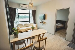 Un espace de vie compact comprenant un coin cuisine, un canapé, une table à manger et un téléviseur fixé au mur.