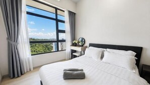 Une chambre d’hôtel avec un grand lit, une table de chevet, une petite table avec une lampe et une fenêtre avec des rideaux.
