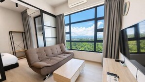 Une pièce comprenant un canapé, une petite table, un lit, un téléviseur et de grandes fenêtres donnant sur un beau paysage.