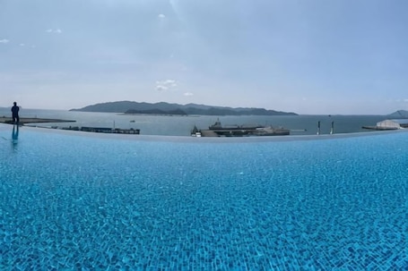 Una grande piscina esterna con acqua cristallina, un molo e una vista lontana della terraferma.. LS Sunset Ocean View Homestay - Jesselton Quay