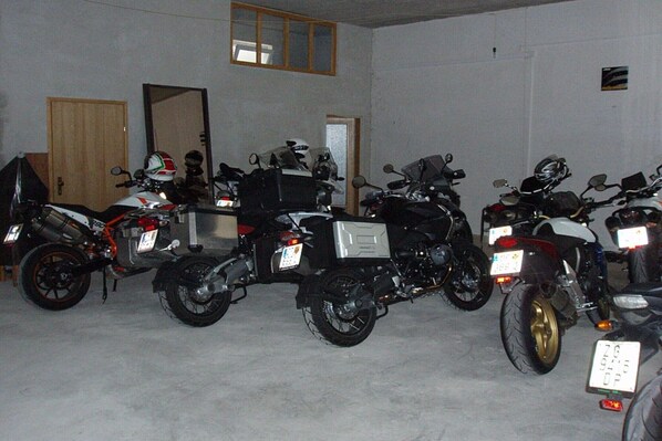 A row of motorcycles parked indoors with a door and a window in the background.