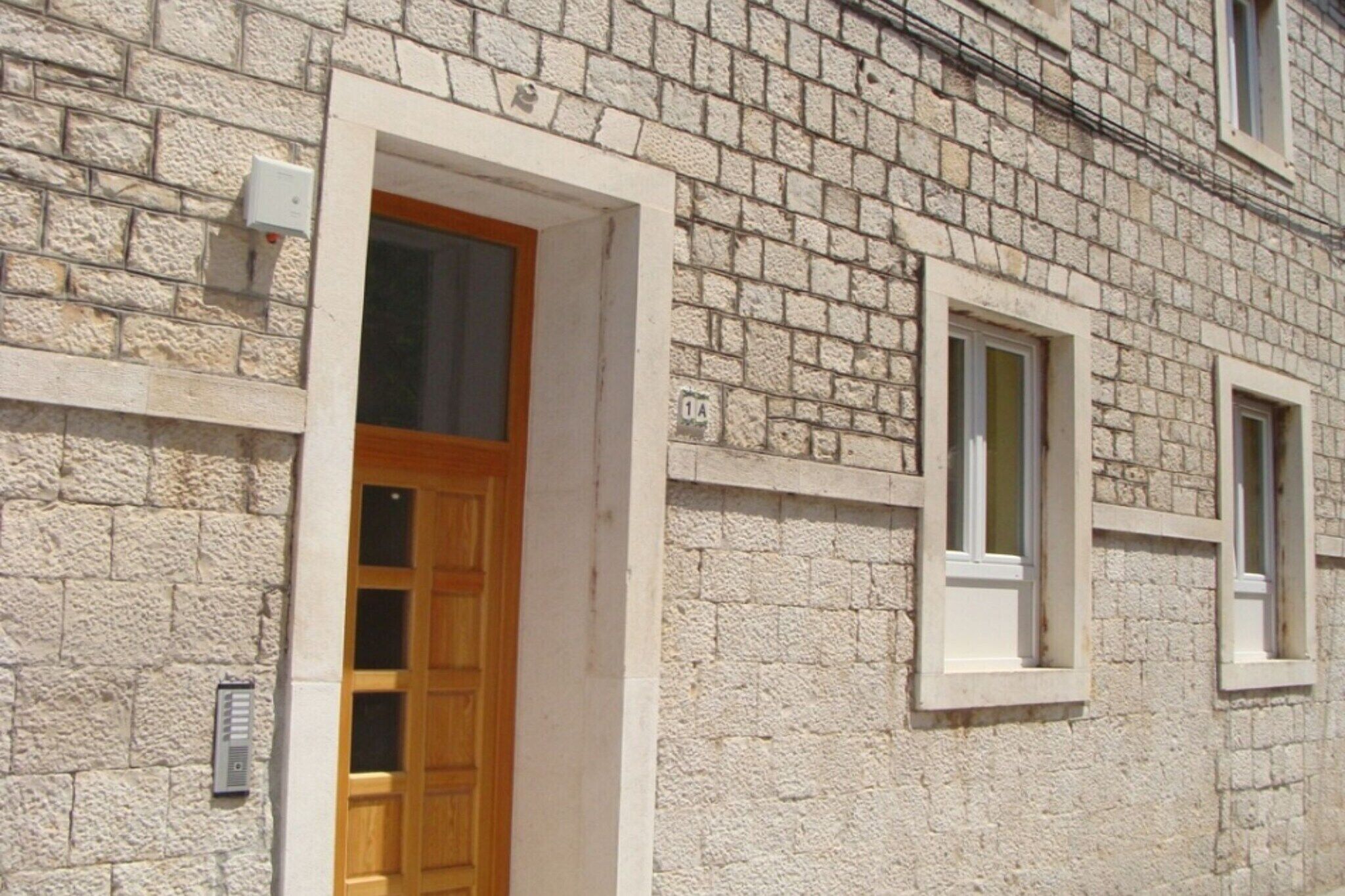 A stone building with a wooden door and two windows.