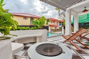 A poolside area with lounge chairs, a circular seating area, and a view of buildings in the background. - Brunsvigia Pool Villa (Pattaya)
