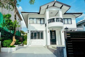 A modern two-story building with a balcony, large windows, and a gated entrance. - Brunsvigia Pool Villa (Pattaya)
