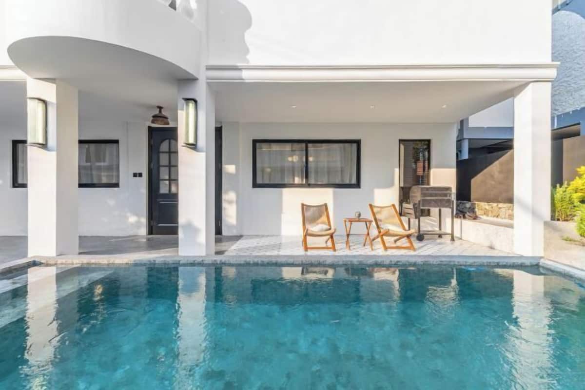 A modern house with a swimming pool, outdoor seating, and a covered patio.