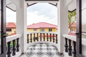 A balcony with a black balustrade and a tiled floor, overlooking a building with a red roof. - Brunsvigia Pool Villa (Pattaya)