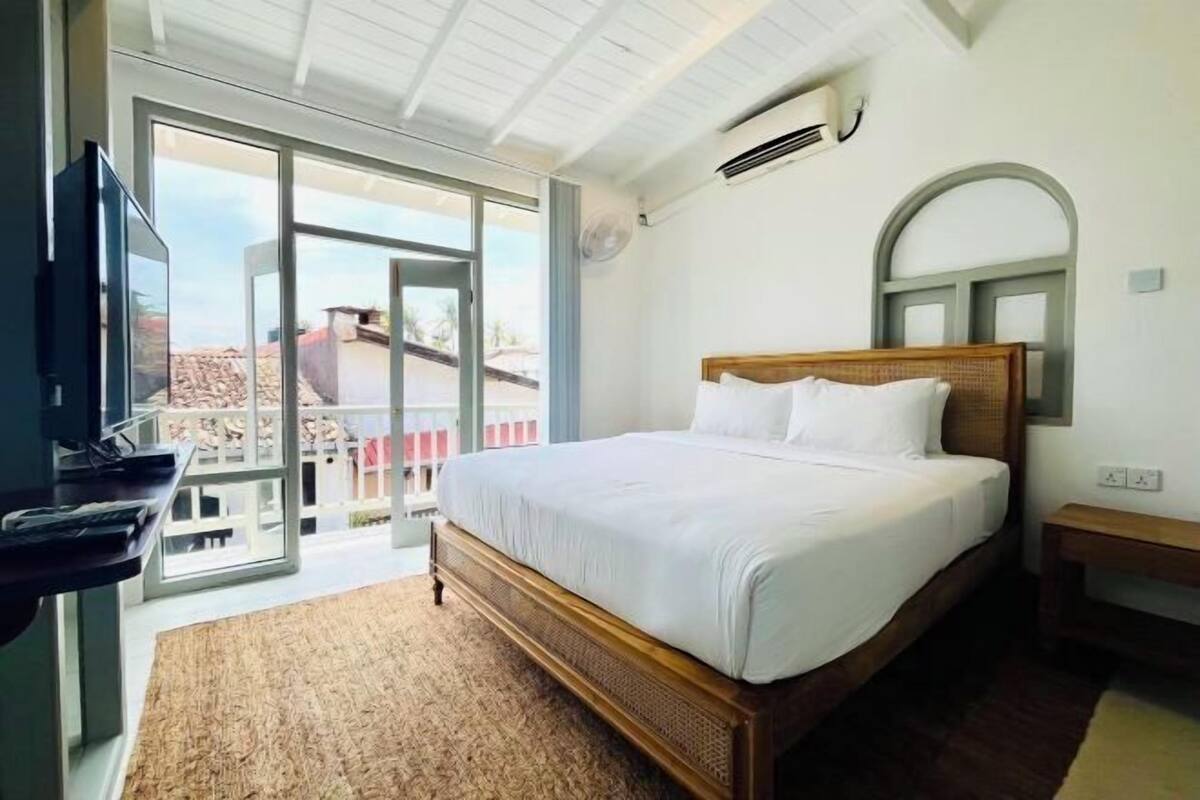 Een slaapkamer met een bed, een televisie, een ventilator en uitzicht door een glazen deur.