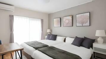 A hotel room with a large bed, two bedside tables, a desk, and a window with curtains.