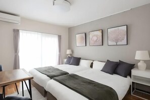 A hotel room with a large bed, two bedside tables, a desk, and a window with curtains. - Garden Lila (Saitama)