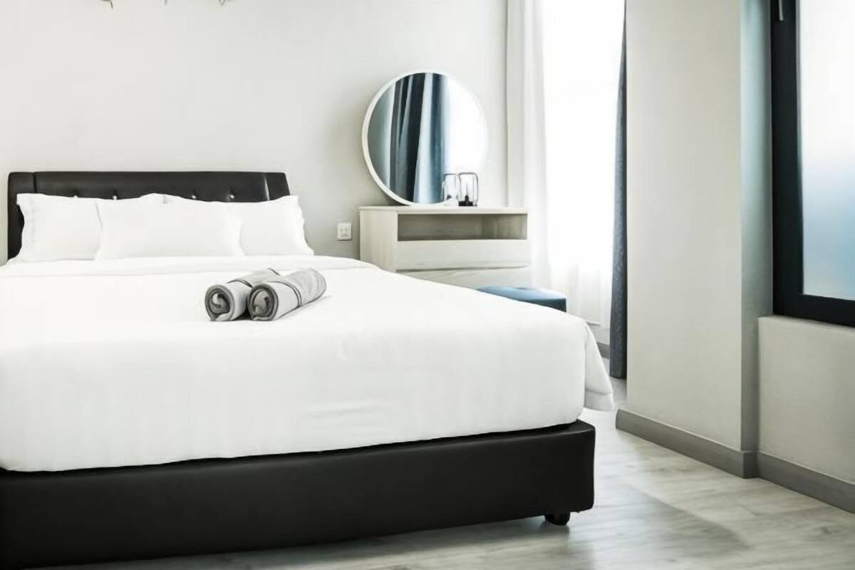 Una habitación de hotel moderna con una cama grande, una mesita de noche, un espejo y una ventana.