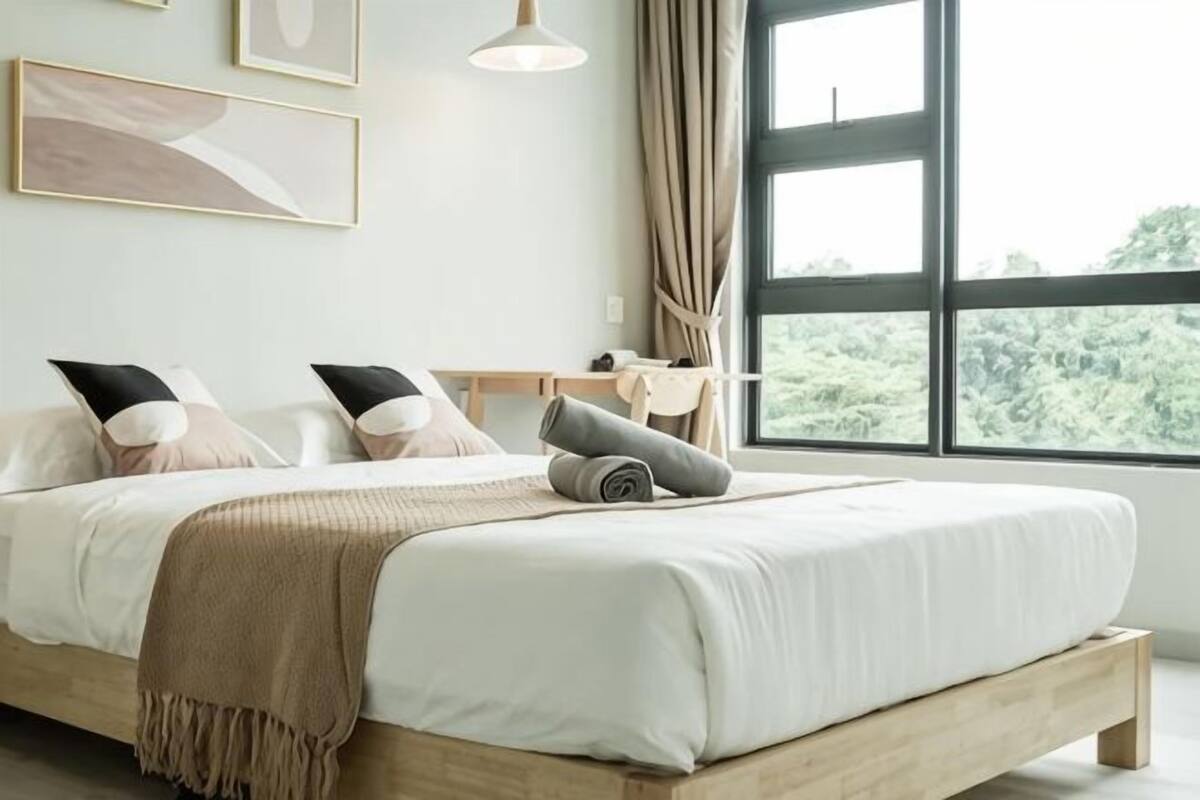 Un dormitorio con una cama, un escritorio y una ventana con vistas a zonas verdes.