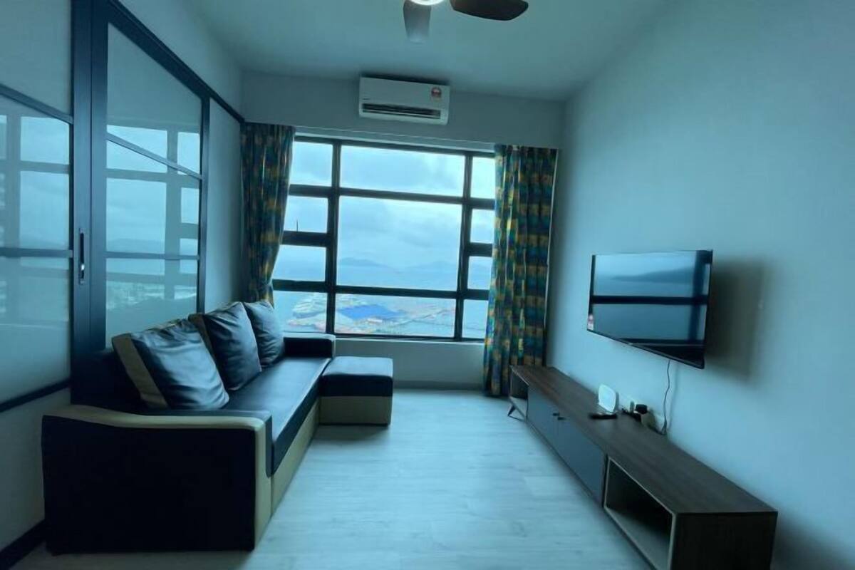 Una habitación moderna con sofá, televisor y un amplio ventanal con vistas.