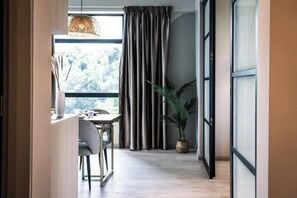 Un interior moderno con zona de comedor, ventanas amplias, cortinas y una planta en maceta.
