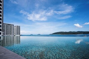 Cielo azzurro limpido, una piscina tranquilla che riflette il cielo e una vista lontana di una catena montuosa.