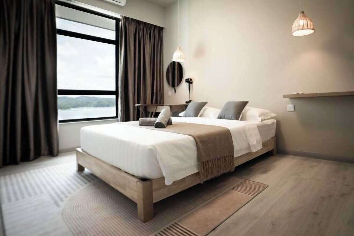 Un dormitorio moderno con una cama grande, vistas al exterior, una mesita de noche y una lámpara.