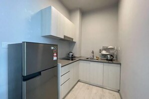 Una cocina compacta con un refrigerador de acero inoxidable, un microondas y un lavamanos.
