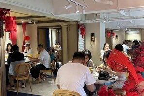 Un'area pranzo con diversi tavoli e sedie, alcune decorate di rosso.