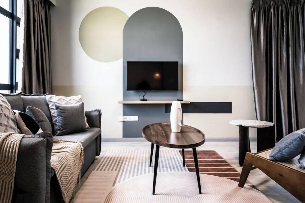 Una sala de estar moderna con un sofá, una mesa de centro y un televisor montado en una pared de diseño arqueado.