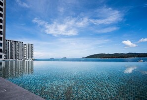 Cel blau clar, una piscina tranquil·la que reflecteix el cel, i una vista llunyana d'un paisatge amb turons.