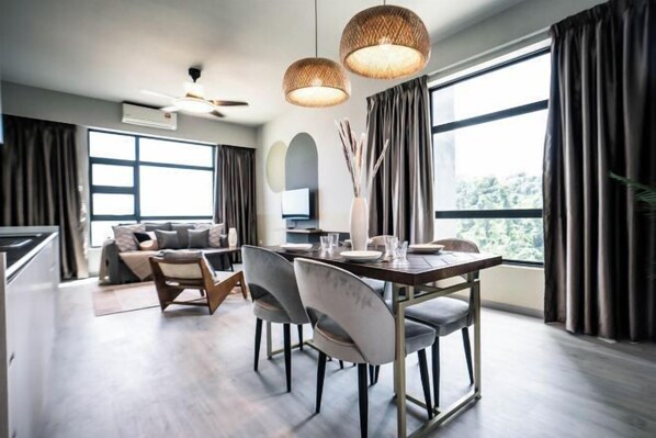 Una sala de estar moderna con una mesa de comedor, sillas, un sofá y un ventanal con cortinas.