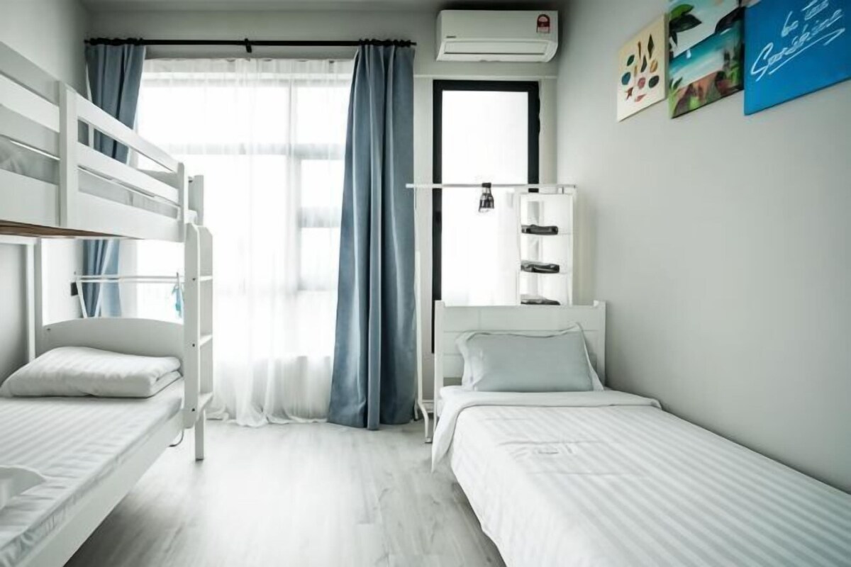 Una habitación con literas, una mesita de noche, una lámpara y un ventanal con cortinas.