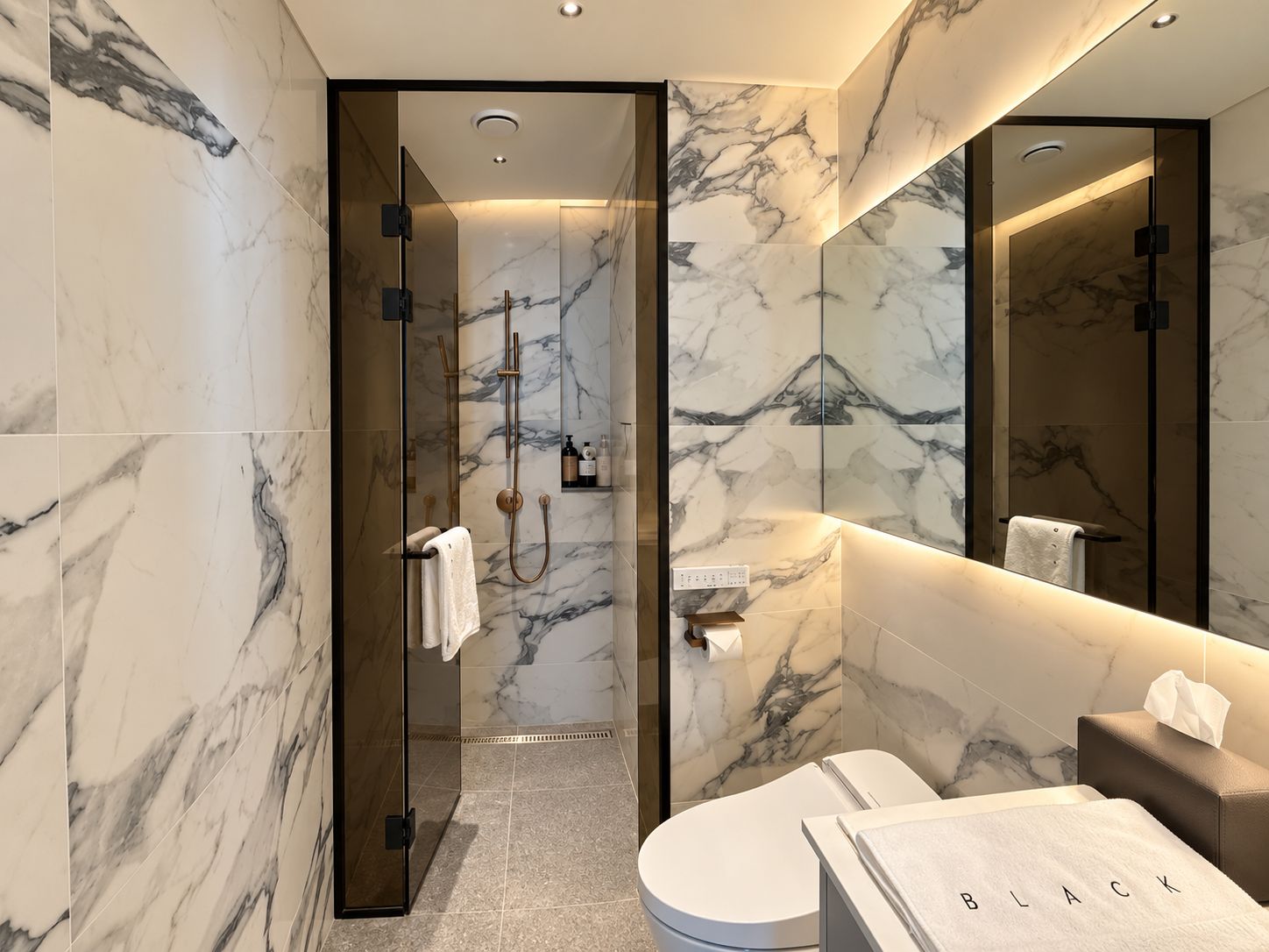 Un baño moderno con ducha envuelta en vidrio, paredes de mármol, inodoro y tocador con espejo.