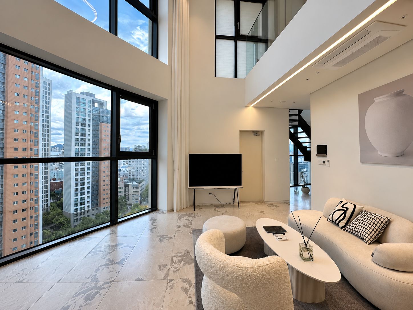 A modern living room with a large window, a flat-screen TV, a sofa, and a coffee table.