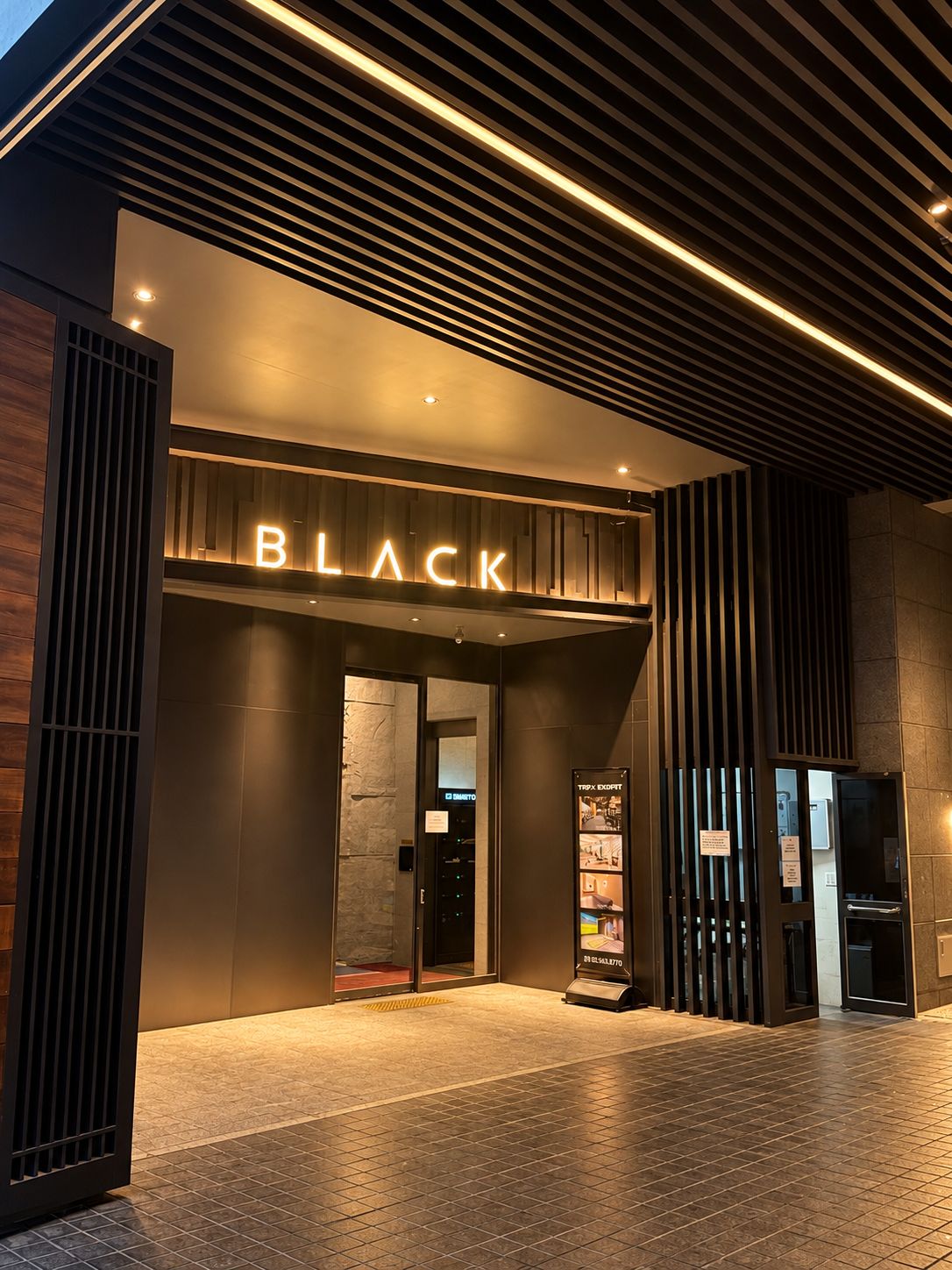 Entrada de un edificio moderno con un llamativo letrero que dice 'BLACK' sobre la puerta.