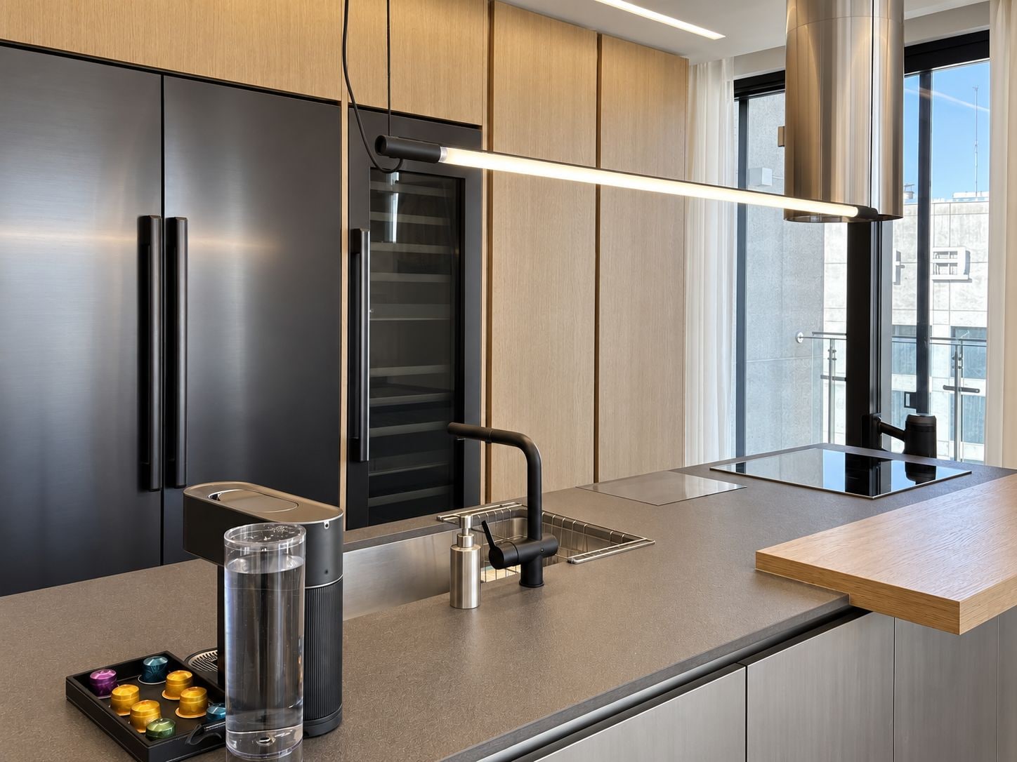 Una cocina moderna con horno empotrado, refrigerador de acero inoxidable y una encimera minimalista.
