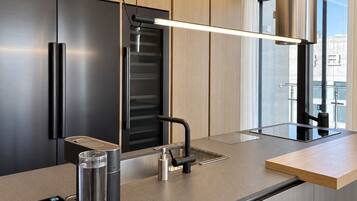 Una cocina moderna con horno empotrado, refrigerador de acero inoxidable y una encimera minimalista.