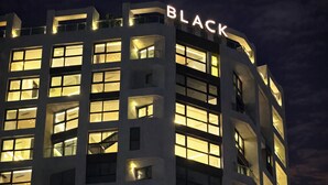 Een meerhoog gebouw met verlichte ramen en het woord "BLACK" opvallend groot op de gevel.