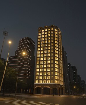 Ein modernes Hotel mit geschwungener Fassade und beleuchteten Fenstern bei Nacht.