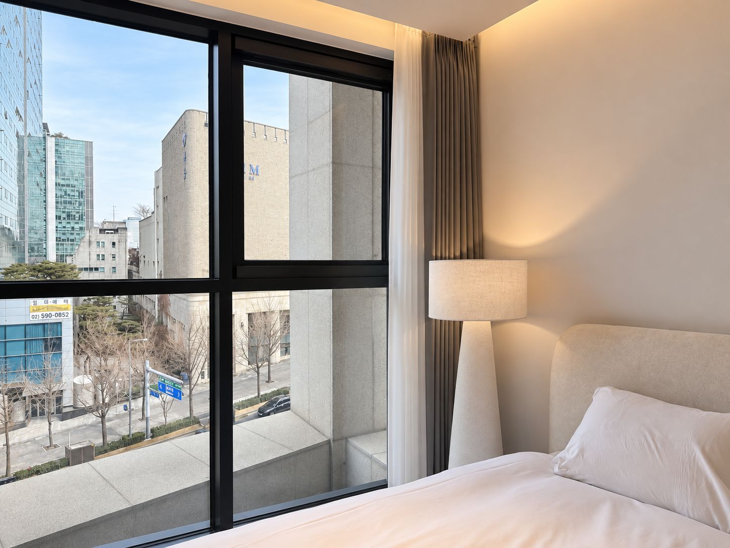 Quarto de hotel com uma janela grande, uma cama e um abajur.