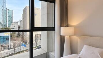Quarto de hotel com uma janela grande, uma cama e um abajur.