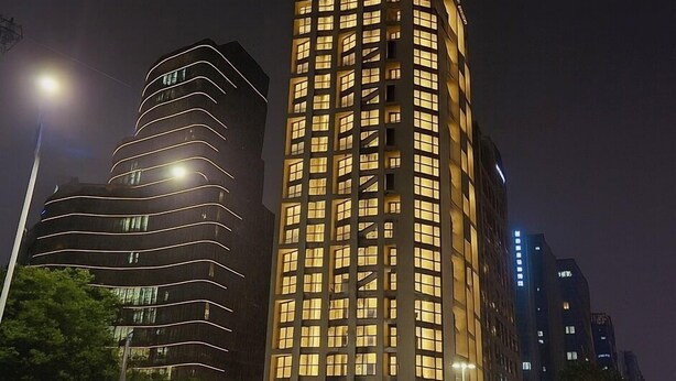 Un hôtel moderne, situé dans un immeuble de grande hauteur, qui se distingue par son entrée en angle et sa façade incurvée.