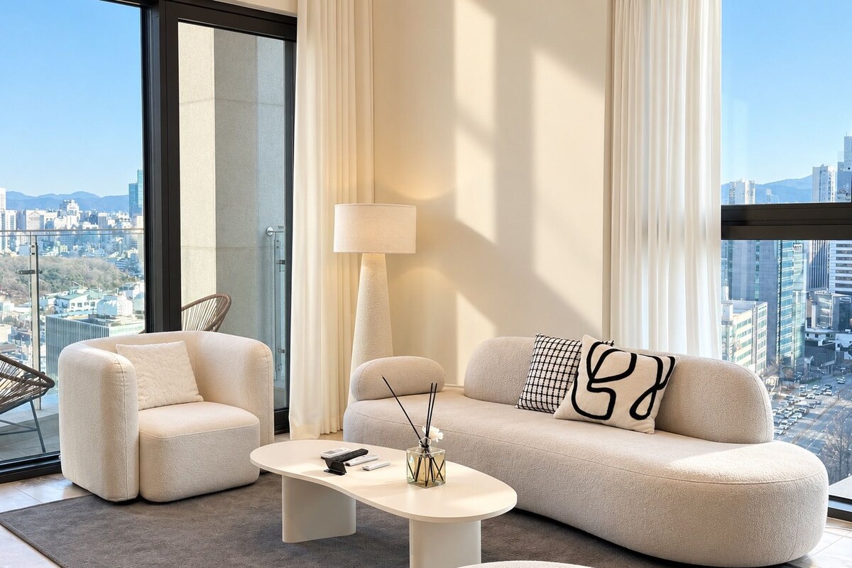 Un salon moderne avec un canapé, des fauteuils, une table basse et un lampadaire.