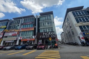 A hotel with a prominent 'hotel first in' sign, a '7-Eleven' store, and a 'Krispy Kreme' outlet. - First In Hotel (Tanjung Dua Belas)
