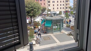A view from a window overlooking a public square with a kiosk, benches, and a building in the background. - La piazzetta Anzio (Anzio)