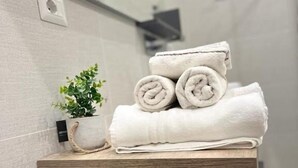 A bathroom with a wooden shelf holding rolled towels and a small potted plant. - La piazzetta Anzio (Anzio)