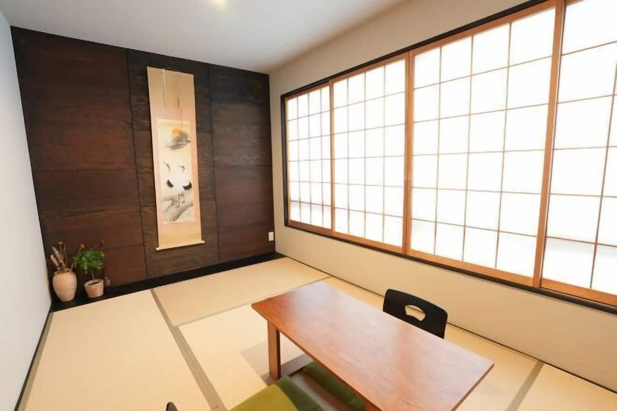 Una habitación japonesa tradicional con suelo de tatami, una mesa baja de madera y una ventana con pantalla shoji.