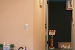 A hallway with a fire alarm and a small shelf with items. - Fuku Guesthouse (Osaka)