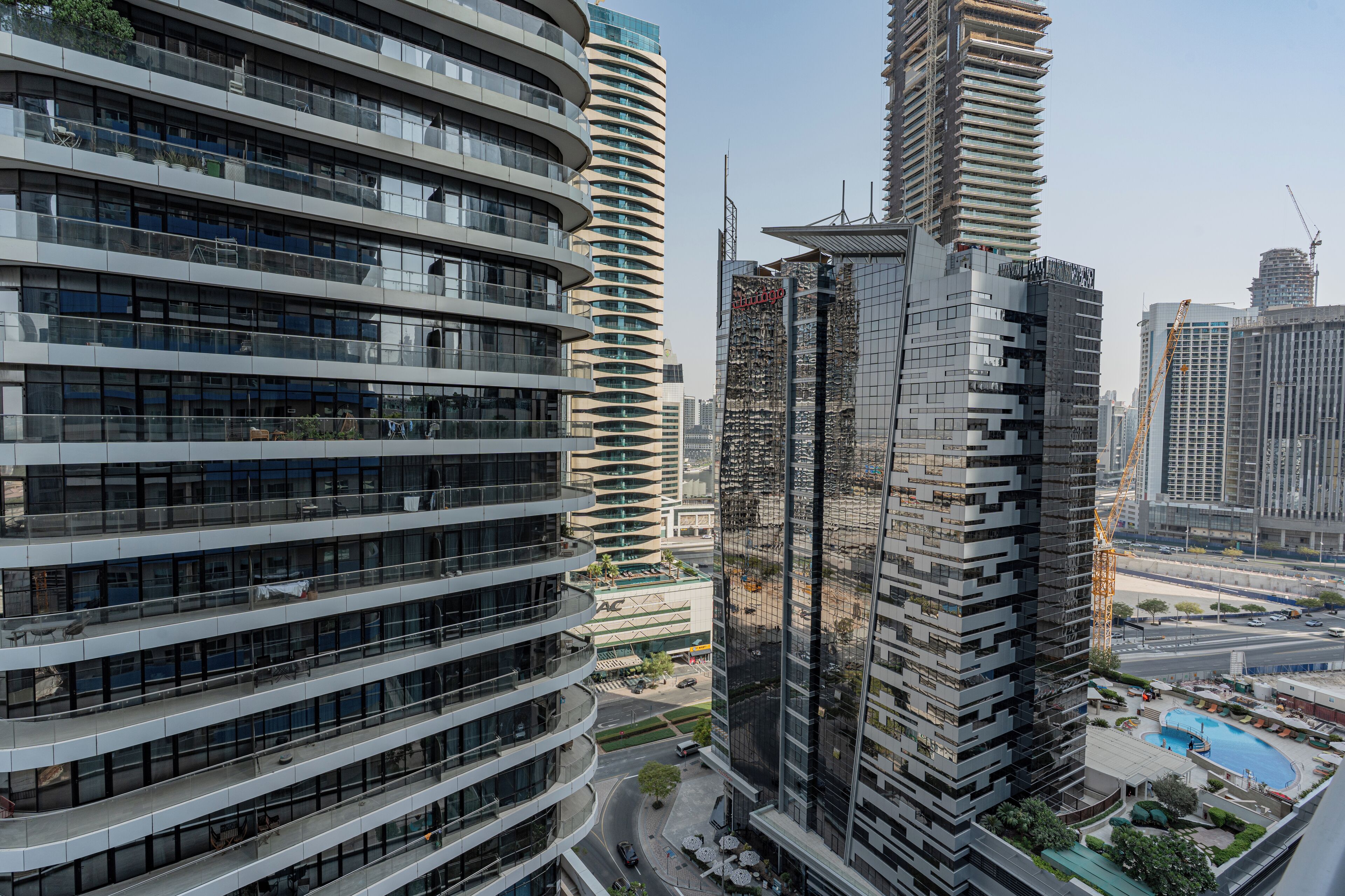 Un immeuble moderne de grande hauteur, doté de nombreux balcons et d’une façade en verre.